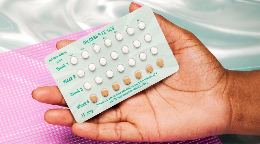 Hand holding birth control pill packet